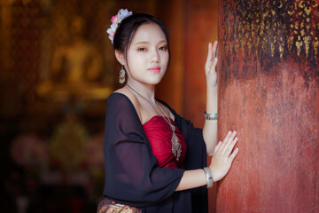 Obraz premium Beautiful Asian Woman in Traditional Lanna Costume at Wat Ton Kwen Ancient Wooden Temple, Chiang Mai, Thailand