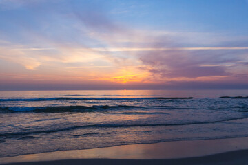 Obraz premium A serene, wide-angle seascape, captures gentle waves lapping onto a sandy shore