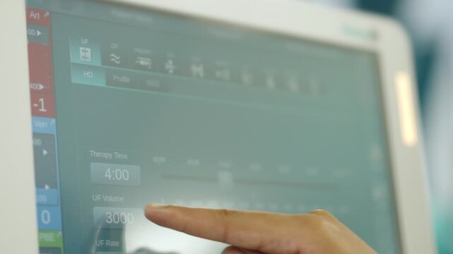 Hemodialysis machine screen as a clinician finger taps the touch display to enter therapy parameters.