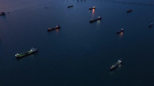  heavy oil tankers and LNG vessels anchored at a strategic maritime chokepoint during a golden sunset, emphasizing global energy crises and petroleum supply chain infrastructure.