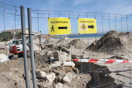 Obra en playa cartel acceso playa en valla reforma dique en paseo mar&iacute;timo con piedras, aporte de arena y escavadora gr&uacute;a m&aacute;quina 
