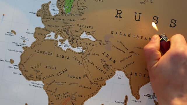 Hand holding a lighter over a world map symbolizing how human decisions can ignite armed conflicts threaten global stability and endanger millions of lives