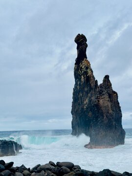 Volcanic sea stack Ilheus da Ribeira da Janela with turquoise crashing wave on north coast of Madeira Portugal