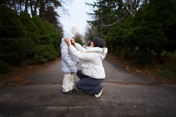 Fototapeta premium Mother adjusting childs hood in a serene outdoor setting on a cool day