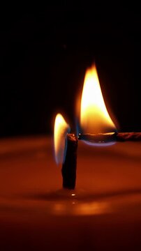 Candle flame in darkness illuminating surroundings