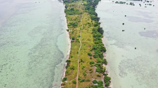 Aerial view of a tropical island archipelago surrounded by clear turquoise sea and coral reefs. Drone shot of an island strip with green trees in the ocean. Pari island in Indonesia 