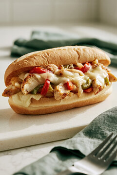 Delicious chicken philly cheesesteak sandwich with melted provolone cheese, sauteed peppers and onions on a hoagie roll