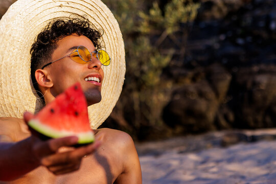 Young man enjoying summer vacation on beach, eating refreshing watermelon
