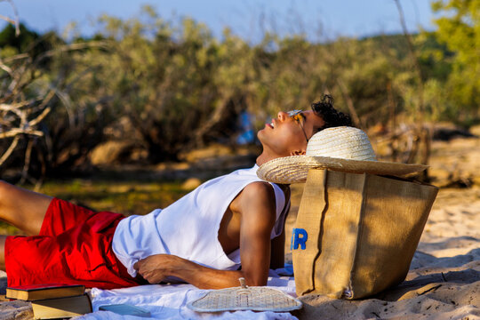 Young man relaxing on beach blanket, sunbathing during summer vacation holiday