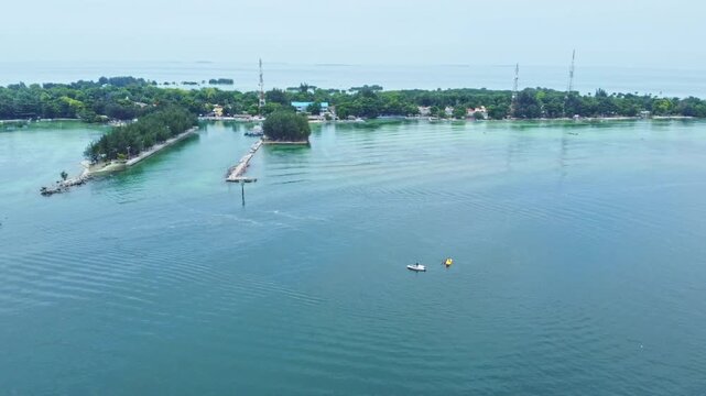 Aerial view of a tropical island archipelago featuring green mangrove forests, shallow coral reefs, and white sand beaches surrounded by a clear turquoise ocean. Pari Island, Indonesia