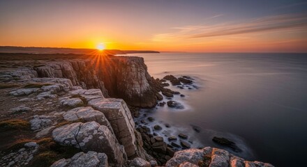 Fototapeta premium Golden sunset over rugged coastal cliffs, long exposure ocean waves, and rocky shoreline at dusk