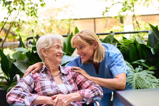 Caregiver Supporting a Senior Woman in a Peaceful Outdoor Rehab Facility
