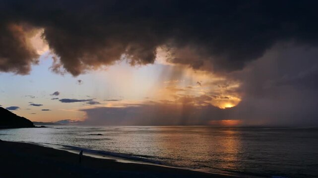10.05.2026, Erromardie, Frankreich. Mann am Strand bei schlechtem Wetter mit Gewitter und Sonnenuntergang an der K&uuml;ste.