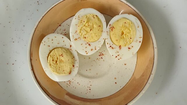 Closeup of hand taking or pick boiled half sliced egg from bunch of eggs served inside plate for eating. Healthy natural protein diet breakfast food for muscle gain and weight gain.