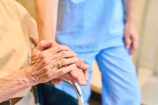 Elder holding hands with caregiver in a healthcare setting