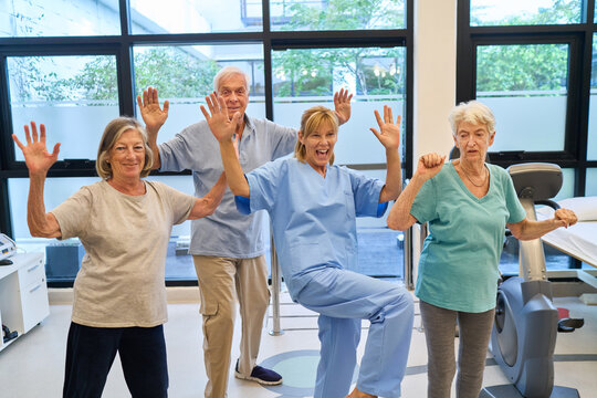 Seniors exercising together in a rehabilitation clinic with a cheerful instructor