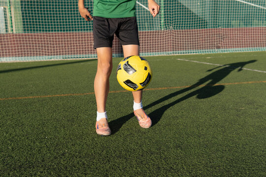 Soccer player training with the ball on an artificial turf pitch.