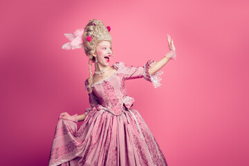 Fototapeta premium Photo of charming positive marie antoinette wear rich dress waving arm hi empty space isolated pink color background
