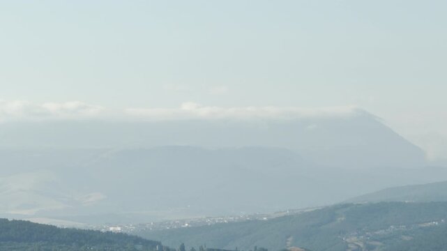 Mount Chatyr-Dag looms majestically over the misty valley seen from Simferopol, Crimea. The serene, pale landscape evokes a deeply peaceful and nostalgic feeling.