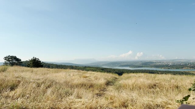 Mount Chatyr-Dag stands quietly on the distant horizon over a sunny reservoir landscape in Simferopol, Crimea. The vast golden fields and blue sky create a deeply peaceful and joyful feeling.