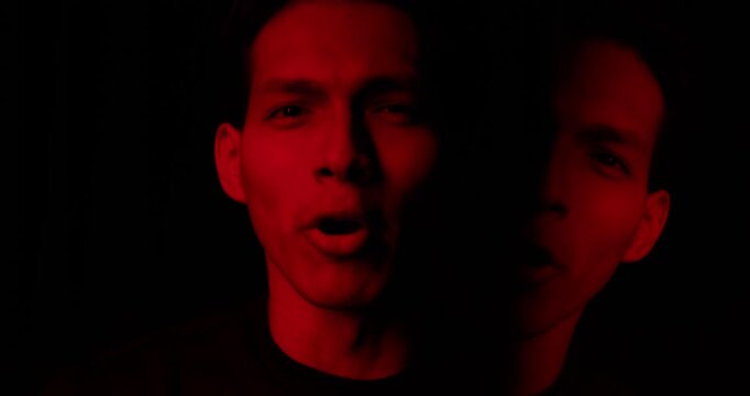 Rapper man read rap in dramatic red light. Portrait of musician star person, aggressive battle. Musical video. Cool brutal performer guy perform hip hop music. Night club party gig. Live show concert.