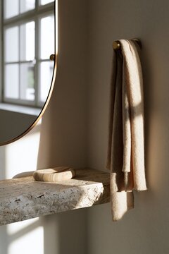 Brass wall hook with cashmere scarf beside round mirror in Scandinavian entryway