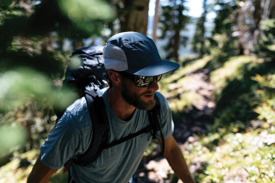 A dedicated male hiker, wearing sunglasses and climbing gear, ascends a beautiful sunlit path flanked by nature, symbolizing commitment to health and adventure.