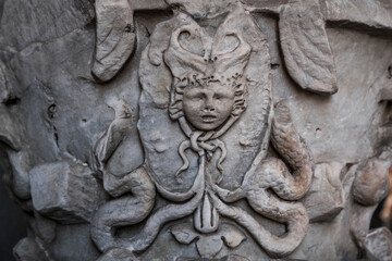 Obraz premium Close-up of weathered stone bas-relief Medusa head with snakes carved on architectural ornament