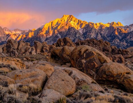 Golden sunrise illuminates jagged mountain peaks and rocky terrain.