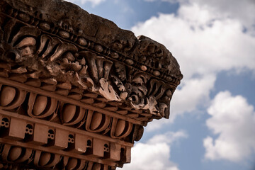 Close-up of ornate carved stone classical architectural capital with acanthus leaf ornament and decorative cornice against cloudy blue sky © PIC by Femke