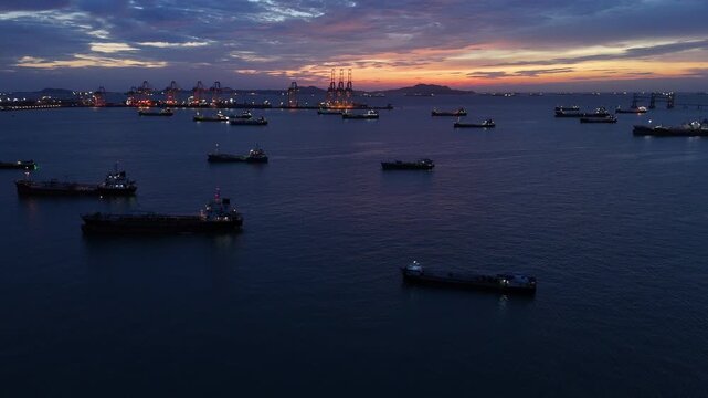  heavy oil tankers and LNG vessels anchored at a strategic maritime chokepoint during a golden sunset, emphasizing global energy crises and petroleum supply chain infrastructure.