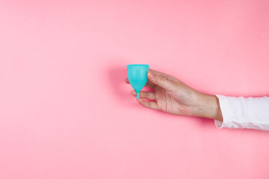 Close Up Of Adult Female Presenting Menstrual Cup Against Pink Background