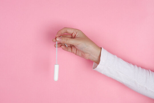 Adult Female Pinches The String Of Cotton Tampon Displaying Disposable Menstrual Protection Options