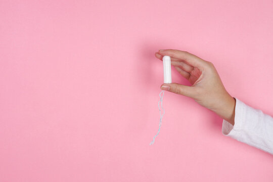 Adult Female Holding Cotton Tampon Against Pink Background