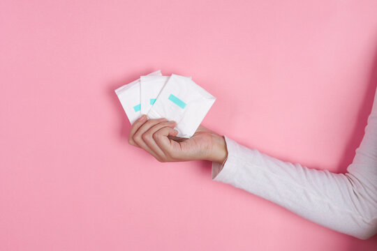 Adult Female Displays Wrapped Menstrual Products Isolated On Pink Background