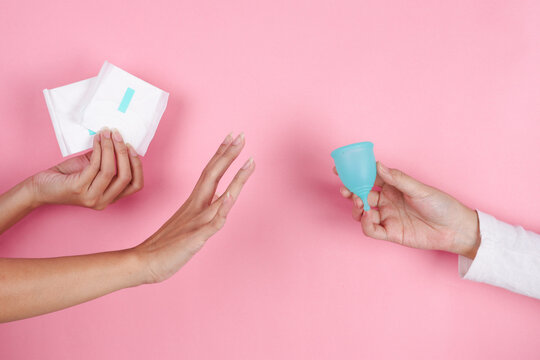 Hand Holding Menstrual Cup Chosen While Another Hand Rejects Disposable Sanitary Pads