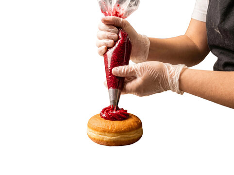Baker piping red jam onto a fresh donut, transparent background