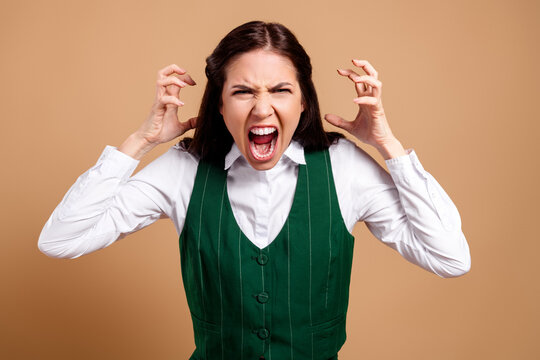 Angry woman yelling in frustration with hands raised, emotional portrait of a professional woman expressing stress, rage and outrage in a studio setting