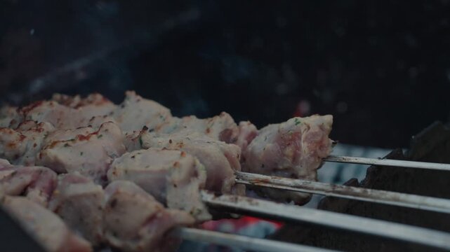 Fresh marinated meat grilling on metal skewers over hot charcoal and open flame