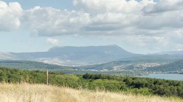 Mount Chatyr-Dag stands grand on the horizon of Simferopol, Crimea. Vast green forests and a blue reservoir rest under heavy clouds, bringing an awe-inspiring feeling of peaceful freedom.