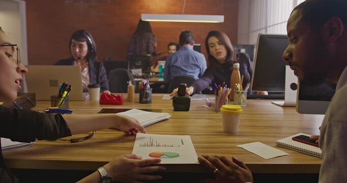 Coworkers exchanging ideas across a shared workspace while colleagues continue working in the