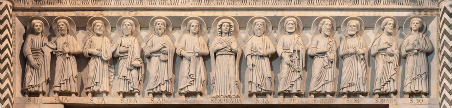 LUCCA, ITALY - JUNE 23, 2026: The medieval stone relief of apostles with the Virgin Mary over the main portal of church Cattedrale di San Martino Nicola Pisano (1257 - 1260)