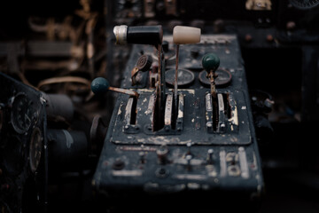 Interior of an abandoned vintage biplane cockpit showing a worn control lever and old aircraft instrument panel in close-up. © Yaroslav