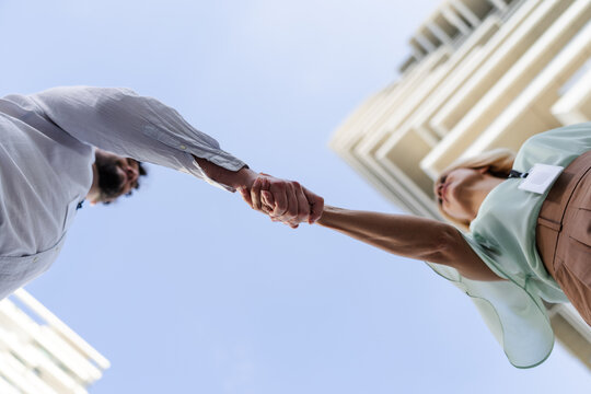 Business professionals shaking hands under modern architecture