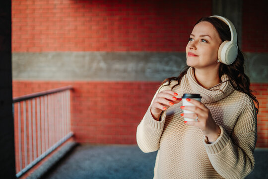 Woman enjoying music and coffee in urban setting