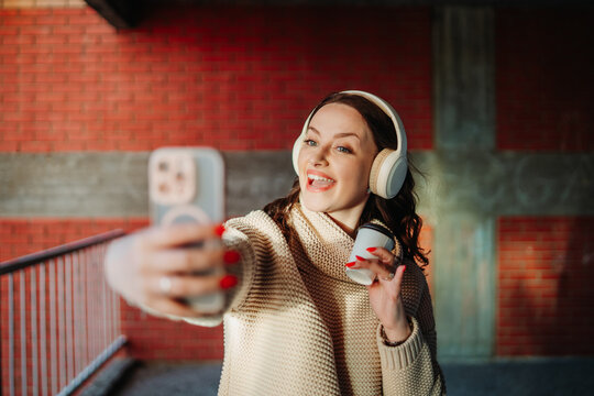 Woman smiling taking selfie with smartphone headphones