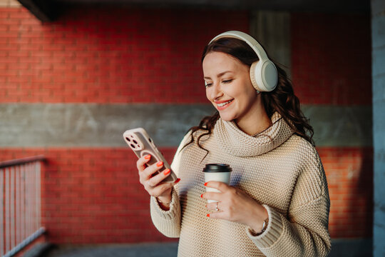 Young woman enjoying music and coffee in urban setting