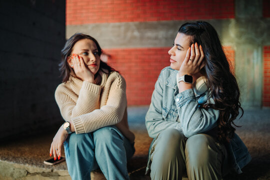 Young adult friends sitting together having serious conversation