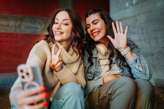 Young women friends making selfie video call outdoors