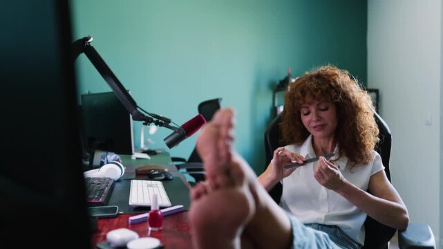 Relaxed female podcaster filing nails before starting work
